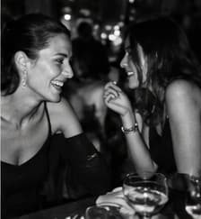 Two women laughing together at dinner, black and white