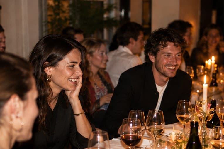 Two guests laughing across a candlelit dinner table