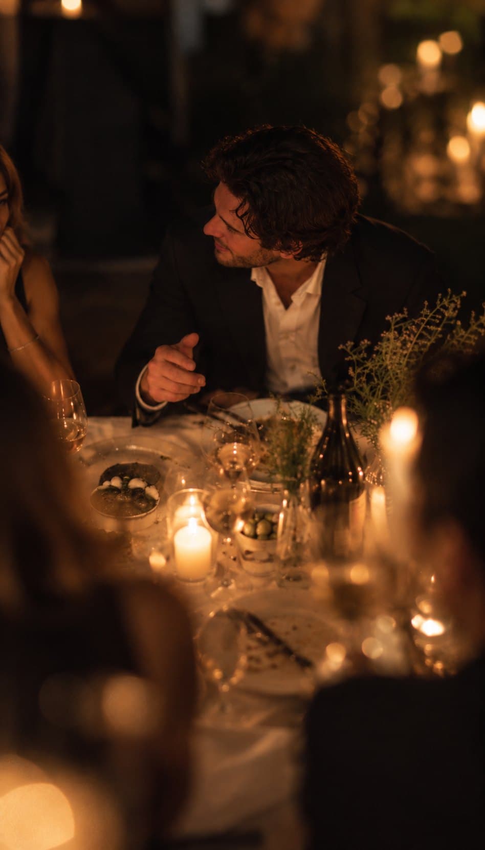 A man turning to listen at a candlelit dinner table