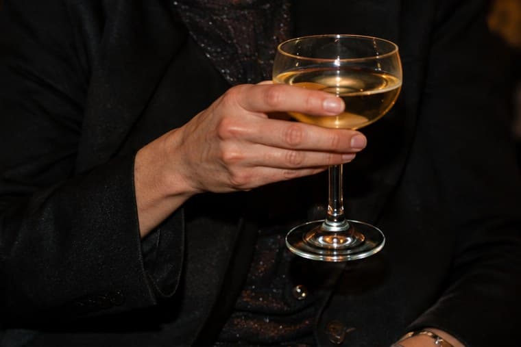 A hand holding a glass of white wine